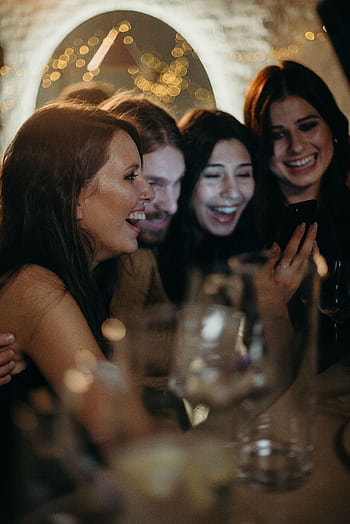 A joyful group of friends enjoying a celebration indoors, sharing laughter and happiness. HD phone wallpaper