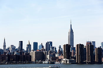 A stunning view of the New York City skyline featuring the iconic Empire State Building under a clear blue sky. HD wallpaper