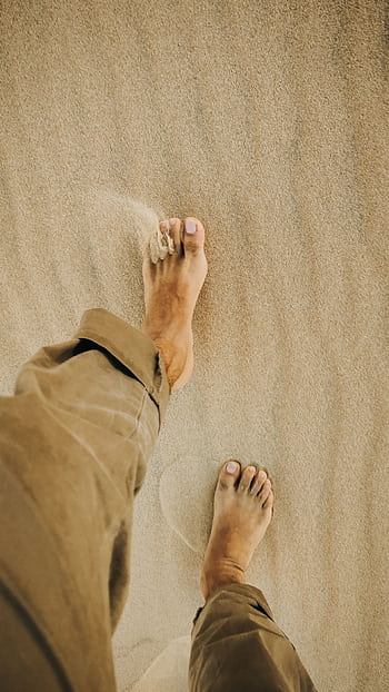 A man walking barefoot on the tranquil desert sand in Qatar, enjoying serene nature. HD phone wallpaper