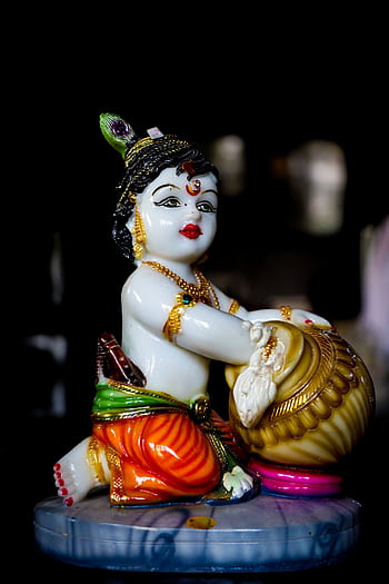 Vivid close-up of a vibrant porcelain Krishna figurine highlighting intricate design and color. HD phone wallpaper