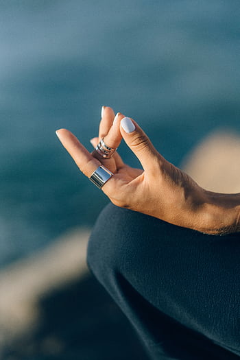 Serene close-up of a hand meditating outdoors with a blurred background. HD phone wallpaper