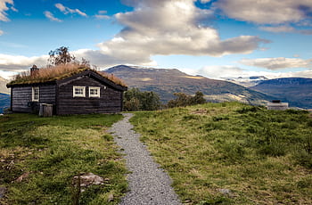 Idyllic rural cabin with grass roof set against breathtaking mountain landscape. HD wallpaper