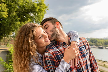 Happy couple sharing a loving embrace outdoors with a scenic background. HD wallpaper