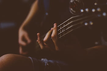 Moody close-up of a hand playing a guitar. Perfect for music-themed projects. HD wallpaper