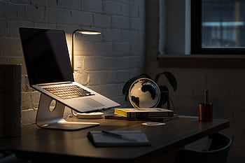 A modern workspace featuring a laptop, books, and ambient lighting for a productive environment. HD wallpaper