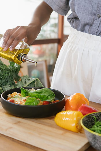 Person drizzles olive oil over fresh vegetable salad on a wooden cutting board. HD phone wallpaper