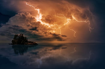 Stunning scene of lightning striking over a small islet at sunset, reflected in calm waters. HD wallpaper