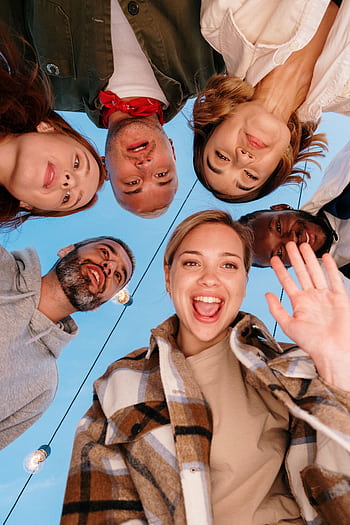 A diverse group of friends smiling into a camera outdoors, capturing a joyful moment. HD phone wallpaper