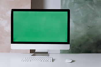 Clean and minimalist setup with a computer and green screen on a white desk. HD wallpaper