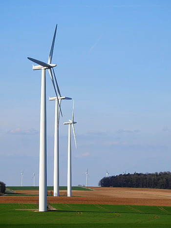 Row of wind turbines in a rural area, generating renewable energy under a blue sky. HD phone wallpaper