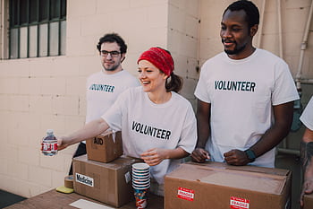 Volunteers distributing aid at an outdoor donation center, promoting social impact and diversity. HD wallpaper
