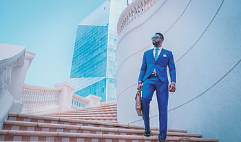 Stylish businessman walking up stairs with skyscraper backdrop in the UAE. HD wallpaper