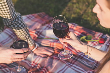 A couple enjoying a romantic picnic with wine and roses on a sunny day outdoors. HD wallpaper