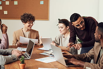 A diverse group of professionals engaged in a collaborative office meeting, sharing ideas and discussing projects. HD wallpaper