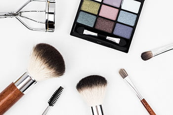 Top view of makeup tools and a colorful eyeshadow palette arranged artistically. HD wallpaper