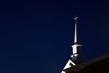 Illuminated church steeple with cross at night. Perfect for religious and architectural themes. HD wallpaper