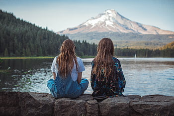 Two women sitting by a lake with a stunning view of Mount Hood in Oregon during sunset. HD wallpaper