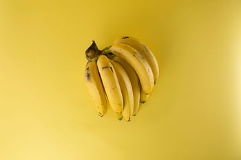 A vibrant bunch of ripe bananas on a matching yellow background, evoking freshness. HD wallpaper
