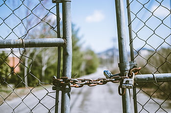 Close-up of a locked chain link fence with rusty chains and padlock, outdoors, in bright daylight. HD wallpaper