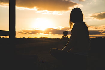 A serene silhouette of a woman meditating at sunset in the Romanian countryside. HD wallpaper