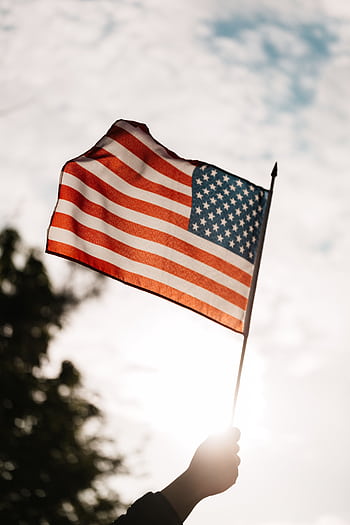 An American flag waving against a bright sky evokes patriotism and dom. HD phone wallpaper