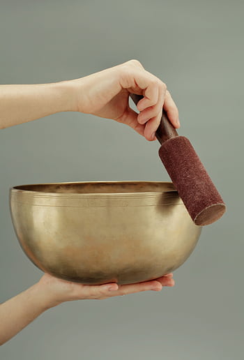 A close-up of hands holding a Tibetan singing bowl, used for sound healing and meditation. HD phone wallpaper