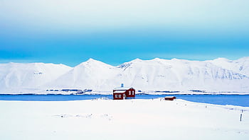A solitary red cabin amidst a vast snowy landscape with blue sky in Iceland, capturing winter's beauty. HD wallpaper