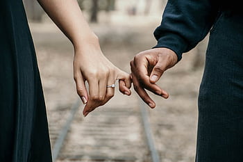 A romantic couple holding hands, symbolizing love and unity on a scenic railtrack. HD wallpaper