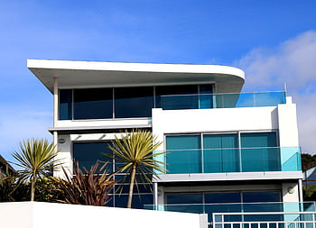 Sleek modern house with glass facade in Poole, UK under blue sky. HD wallpaper