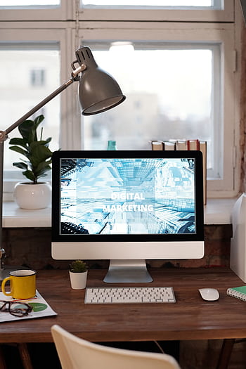 Contemporary home office desk with digital marketing screen, perfect for remote work inspiration. HD phone wallpaper