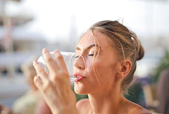 Close-up of a woman drinking water with a serene expression outdoors. HD wallpaper