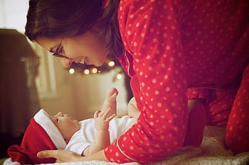A joyful moment captured as a mother and baby in red pajamas enjoy their first Christmas indoors. HD wallpaper