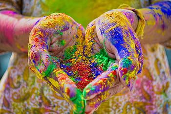 Close-up of colorful hands holding vivid Holi festival powder showcasing vibrant celebration. HD wallpaper