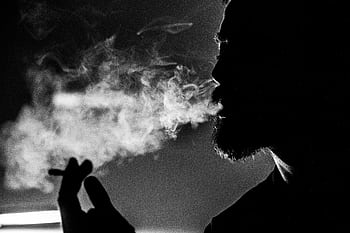 Dramatic black and white of a man's silhouette exhaling smoke, creating an atmospheric effect. HD wallpaper