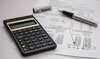 Close-up of financial documents with calculator and pen, ideal for business management themes. HD wallpaper