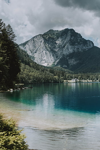 Serene mountain lake surrounded by lush forest and majestic peaks under a cloudy sky. HD phone wallpaper