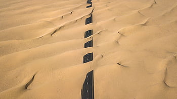 Stunning aerial shot of a road cutting through the sand dunes in Dubai's desert. HD wallpaper