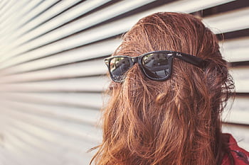 Fashionable woman with sunglasses, face hidden by hair, standing outdoors. HD wallpaper