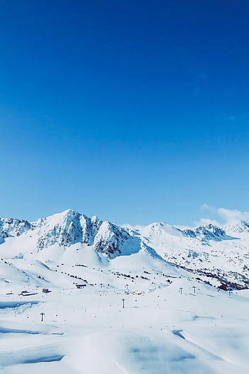 Majestic snowy mountains in Andorra under a vibrant blue sky, perfect for winter sports. HD phone wallpaper