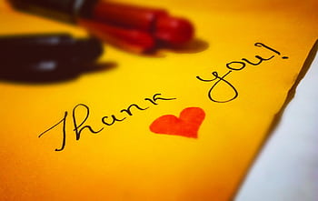 Close-up of a thank you note with a heart and pen on colored paper. HD wallpaper