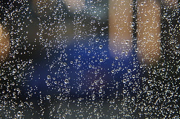 Macro shot capturing raindrops on glass with a blurred background. HD wallpaper