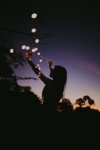 Silhouette of a woman holding fairy lights against a twilight sky in São Paulo, creating a magical mood. HD phone wallpaper