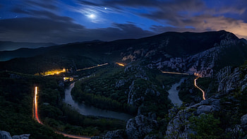 road following a serpentine river at night, night, river, hills, lights, road, rocks HD wallpaper