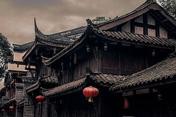 Historic Chinese building with ornate roofs and red lanterns under cloudy skies. HD wallpaper