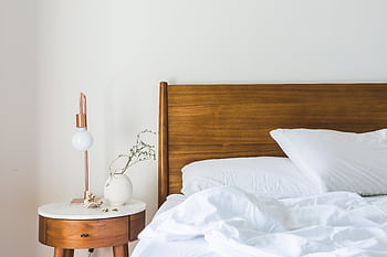 A minimalist bedroom features a wooden headboard, white bedding, and a stylish side table lamp. HD wallpaper