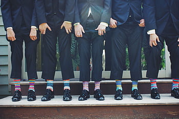 A fun group of men in formal suits showing off colorful socks, perfect for wedding vibes. HD wallpaper