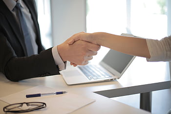 Close-up of a professional handshake over a laptop during a business meeting in an office. HD wallpaper