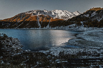 Peaceful winter landscape of a snow-covered mountain lake with clear reflections at dusk. HD wallpaper