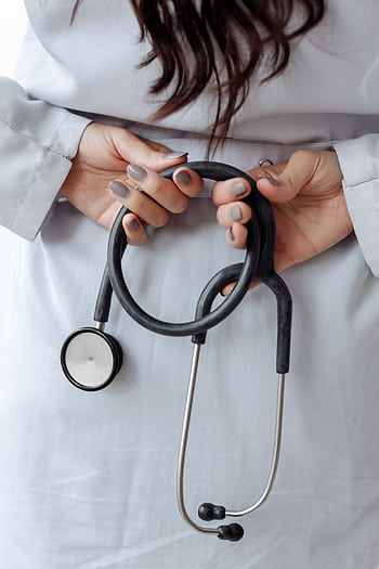 Close-up shot of a doctor holding a stethoscope with both hands, wearing a white coat. HD phone wallpaper