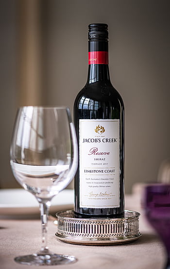 Close-up of wine bottle and glass on a dining table. Elegant dining setup indoors. HD phone wallpaper